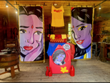 Two large face paintings on walls with a colorful washing machine in front and an antique one on the left.