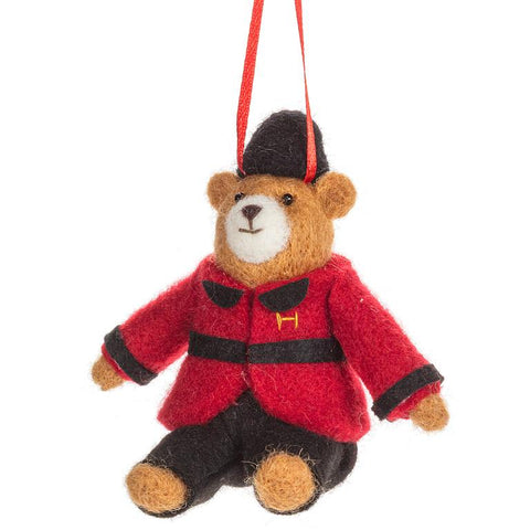 Felted bear ornament wearing a red coat and black hat on a white background