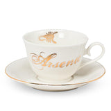 Tea cup and saucer with gold trim. Cup has the word Arsenic on it and a scorpion on the inside in gold