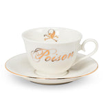 Tea cup and saucer with gold trim. Cup has the word Poison on it and a skull and crossbones on the inside in gold