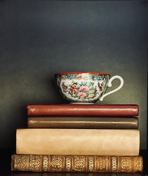 Vintage floral teacup sitting on a stack of old books