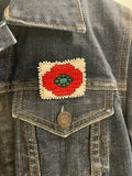 Denim jacket with a beaded red poppy pin on the chest pocket