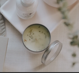Candle in a metal container with sweetgrass on the surface.