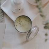 Candle in a metal container with sweetgrass on the surface.