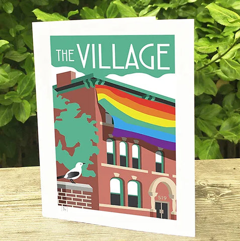 Note Card with a picture of a building with a rainbow flag resting on a wooden table.