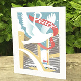 Holiday card showing Toronto City Hall with a dove holding a red ribbon with Peace written on it.
