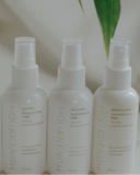 Three white spray bottles with labels on a light background