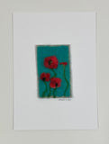 Felted artwork of red poppies on a turquoise blue.