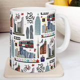 White mug with Toronto-themed design featuring landmarks and text on a white surface.