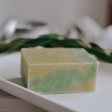 Green and yellow soap bar on a white plate with a blurred background