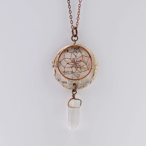 Close up of birch bark pendant necklace with dream catcher and quartz crystal