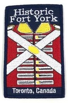 Navy blue iron on badge with embroidered image of Red Coat in centre. Historic Fort York embroidered in white at top. Toronto, Canada emroidered in white at bottom.