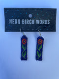 Close product shot of beaded earrings shown with red flower on navy blue background 