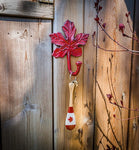 Maple leaf shaped iron hook mounted on fence with key and keychain hanging from hook.