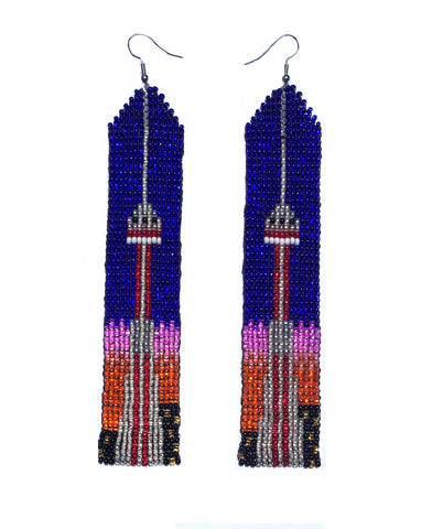 Close up image of beaded earrings with the CN Tower at sunset