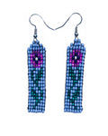 Close product shot of beaded earrings shown with pink flower on lavender background 