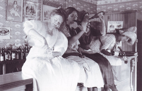 Postcard with photo of four woman sitting on bar