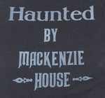 Close product shot of Haunted by Mackenzie House printed in white lettering on a black t-shirt