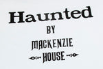 Close up of Haunted by Mackenzie House printed in black lettering on a white t-shirt