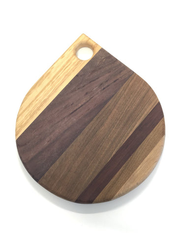 A Board in the shape of tear drop with a circular hole at the top.  Made with stripes of different wood. 