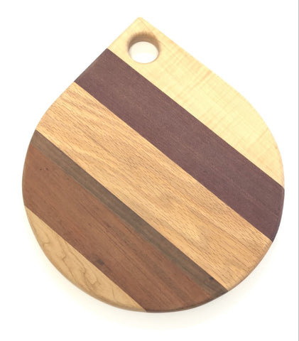 A Board in the shape of tear drop with a circular hole at the top. Made of Stripes of different wood.
