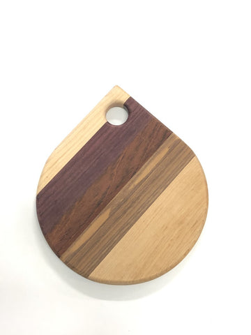 A Board in the shape of tear drop with a circular hole at the top. Stripes of different wood in the centre. 