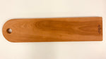 A Baguette Board made with Cherry Wood. Hand Crafted in Canada is printed on the bottom edge (1).