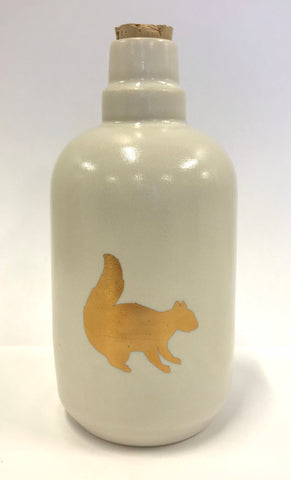 White bottle with gold squirrel design.