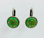 Vintage button hanging earrings with gold flowers on a green background