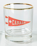 Gold rimmed bar glass with a vintage picture of a Canada Pennant on it